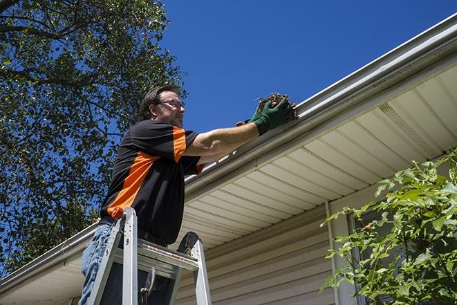 a gutter repair technician using a ladder and tools in Abington MA